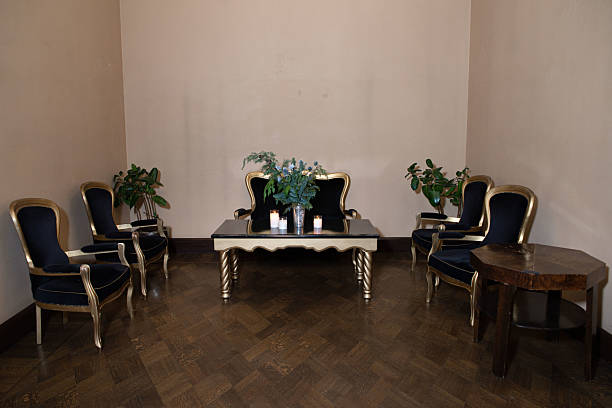 A sophisticated lounge setup featuring black and gold vintage armchairs, a central table with candles, and floral décor.