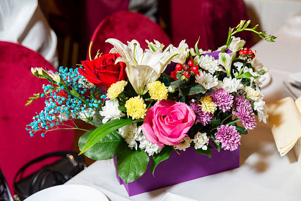 Bright multicolored flower arrangement in a purple box used as a decorative centerpiece for a festive or formal table setting.