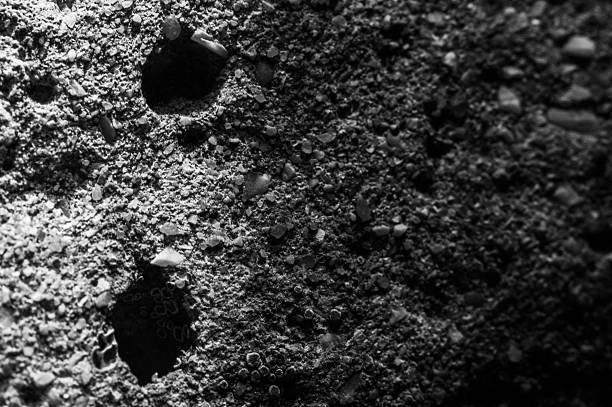 A close-up of a stone shows its relief. The stone surface has small patterns. The stone looks uneven. Marble, silicon, limestone, sandstone.