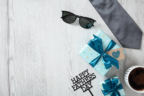 istock Father's day morning setting: wrapped presents, grey tie, sunglasses, and coffee cup with copy space 2217180630