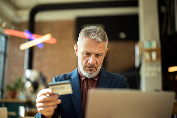 istock Focused businessman making online payment using credit card and laptop in modern office 2217186574