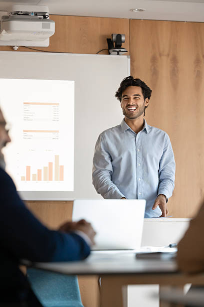 Man giving presentation, stands at lectern next to projection screen