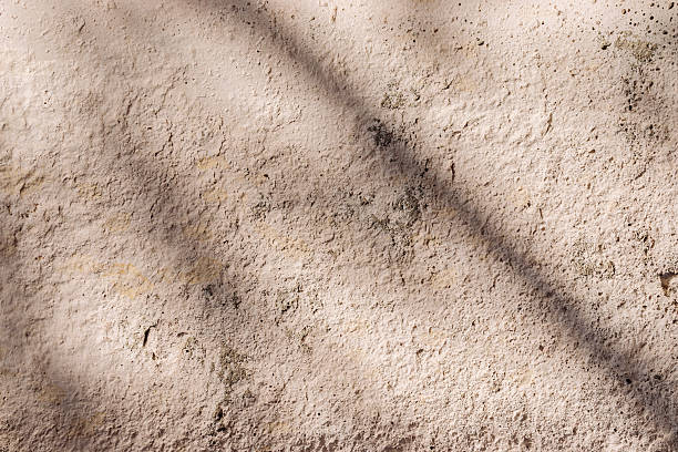 istock Diagonal shadows on a painted light beige old concrete wall on a sunny summer day 2217191386