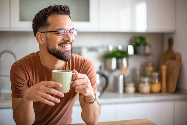 istock Smiling bearded man enjoying a cup of coffee in his modern kitchen 2217191586