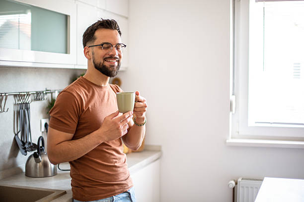 istock Young man enjoying a cup of coffee in his modern kitchen 2217191625