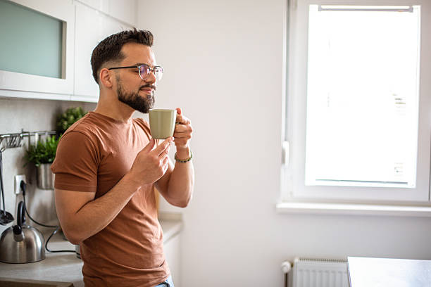 istock Young man enjoying a cup of coffee in his modern kitchen 2217191638