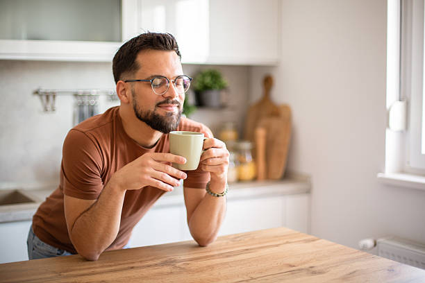 istock Young man enjoying a cup of coffee in his modern kitchen 2217191645
