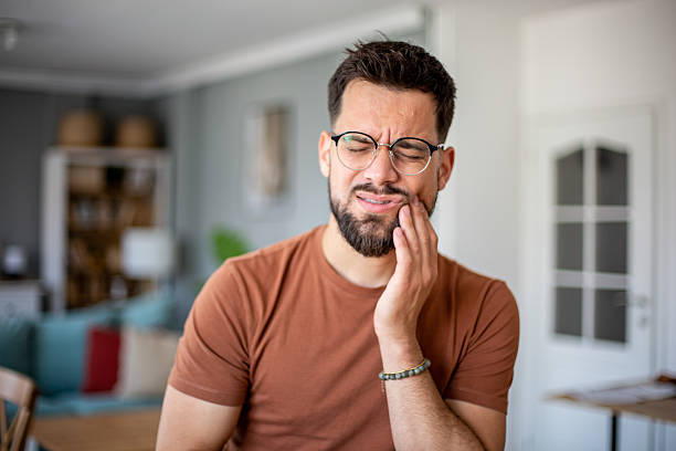 Young man suffering from strong tooth pain at home