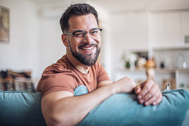 istock Happy young man smiling and relaxing on sofa at home 2217193180