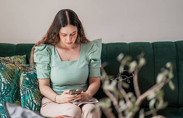 istock Young woman concentrating using cell phone while working from a sofa at home. 2217193542