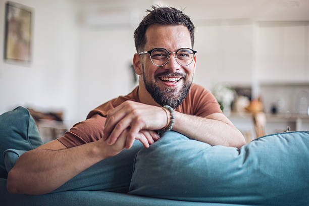 istock Young man relaxing on sofa at home smiling at camera 2217193588
