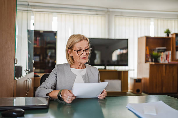 istock mature woman teacher read a document, file on workplace in the library 2217194676