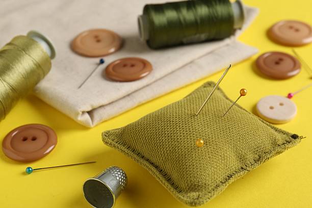 Different sewing supplies on yellow background, closeup