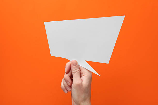 istock Woman holding blank speech bubble on orange background, closeup. Space for text 2217198756