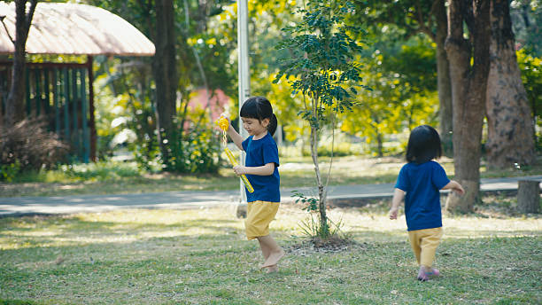 Kids run around chairs playing a game outside in summer period