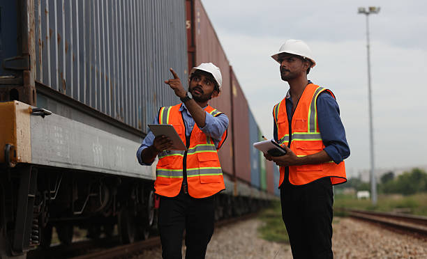 istock Two Indian logistic staff with safety jacket and PPE check container on rail transportation ,World wide logistic, The container cargo shipment by rail transportation , Logistic manager and staff working check container on rail way 2217202044