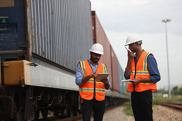 istock Two Indian logistic staff with safety jacket and PPE check container on rail transportation ,World wide logistic, The container cargo shipment by rail transportation , Logistic manager and staff working check container on rail way 2217202056