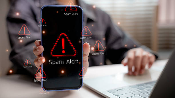 istock Person holding smartphone with multiple red spam alert warning icons on screen, representing mobile cybersecurity, phishing threats, scam detection, and digital safety awareness. 2217203188