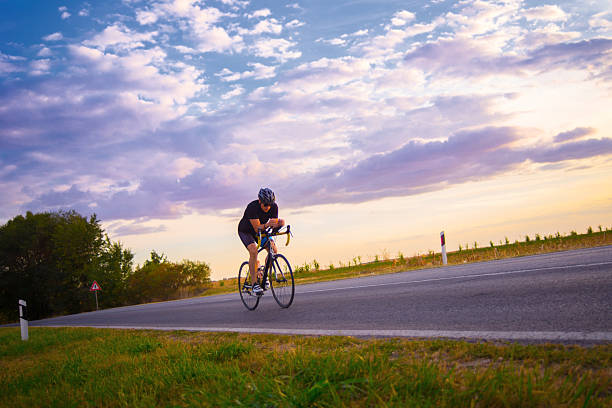 Young man cycling on the road on a sunny summer day.