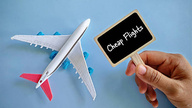 istock a hand holding notification board written with 'Cheap Flight' with toy airplane beside it. 2217208734