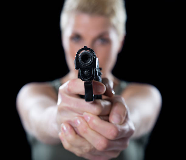 Woman shooting with the gun isolated on black background