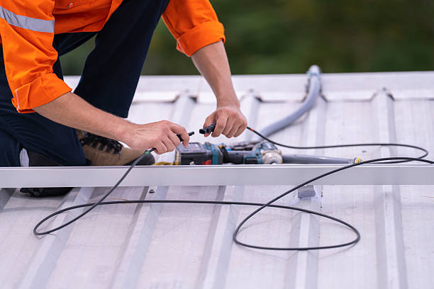istock Technician in an orange safety uniform and helmet handling an electrical cable on a rooftop. Represents safety, professionalism, and expertise in renewable energy installations and maintenance work. 2217212297