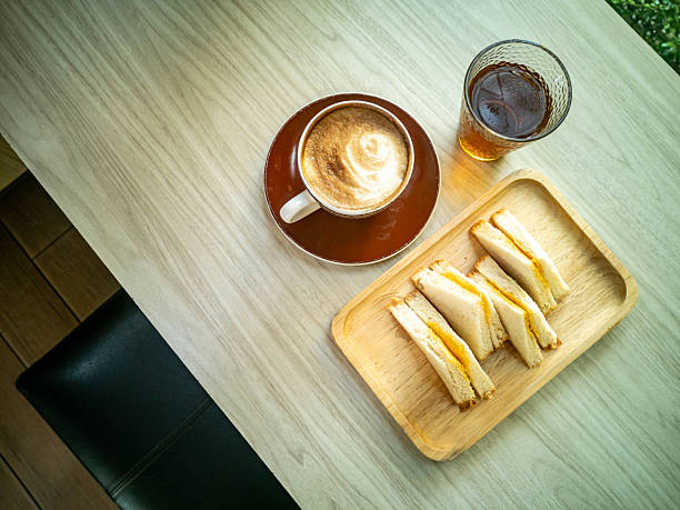 A cozy morning scene featuring a cup of coffee and a plate of sandwiches, ideal for showcasing breakfast time or cafe culture. Perfect for food enthusiasts.