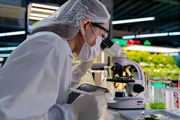 A researcher in a sterile lab conducts a scientific experiment using a microscope and test tubes. Cutting edge biotechnology and chemistry help develop breakthroughs in medicine and healthcare.
