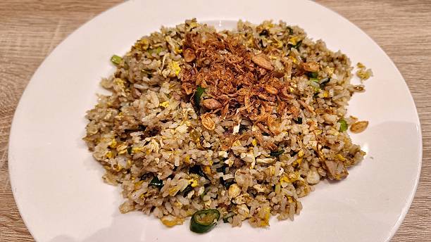 Delicious fried rice topped with scrambled egg and fried onions served on a white plate