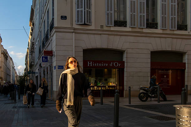 Marseille, France March 15, 2025 A young woman walks down Rue Paradis in the sunset.
