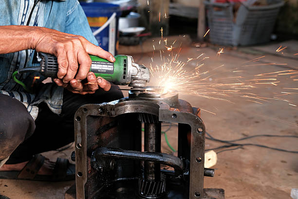 Closeup Of Hands Using Grinding Tool On Metal Part Outdoors