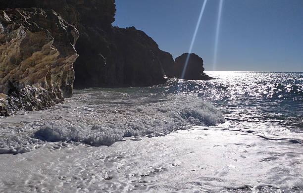 istock Serene ocean scene with sparkling waves lapping against rocky cliffs under a bright, sunny sky. Evokes tranquility, escape, and natural beauty. Ideal for travel. 2217224609