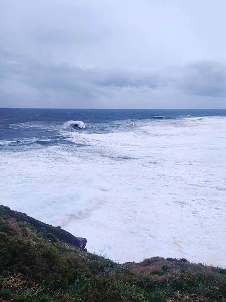 istock Dramatic seascape featuring powerful waves crashing against a rugged coastline under a stormy sky. Evokes strength, resilience, and the untamed beauty of nature. 2217224674