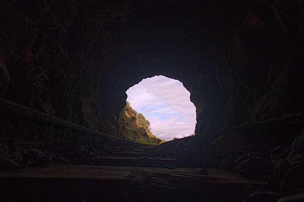 istock Scenic view from inside a railway tunnel looking out to a cloudy sky and lush greenery 2217226753