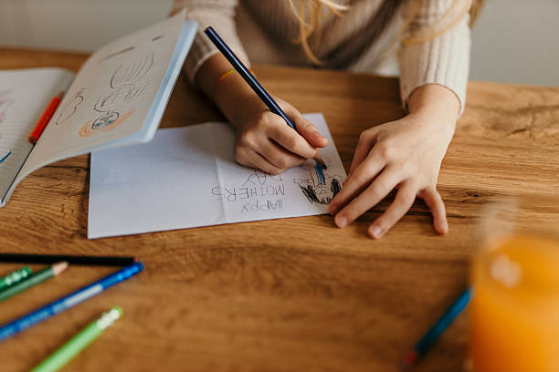 istock Child drawing a mother's day card at the table with colored pencils 2217233401