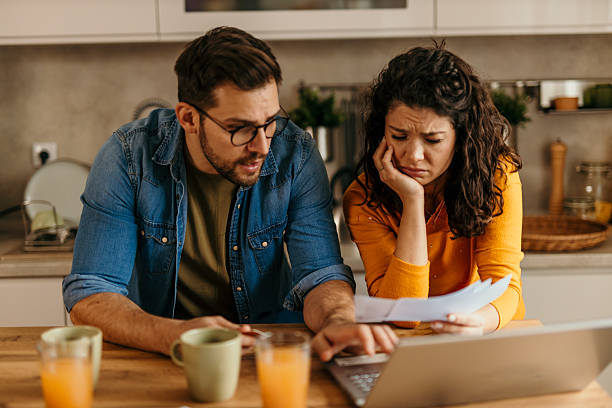 istock Worried couple managing domestic bills using laptop in kitchen 2217233479