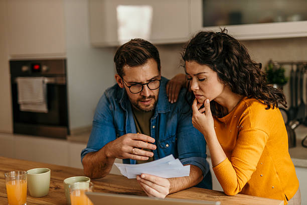 istock Worried couple examining bills in kitchen facing financial problems 2217233505
