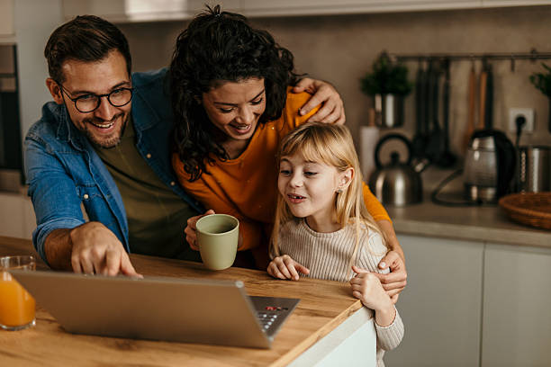 istock Happy family watching something on laptop in kitchen 2217233660