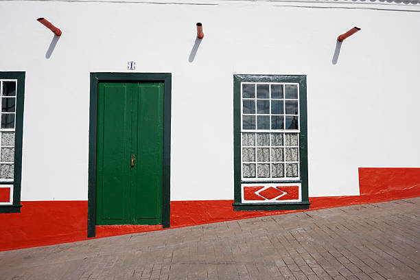 istock Minimalist facade with green door and patterned window on a sloped street 2217236079