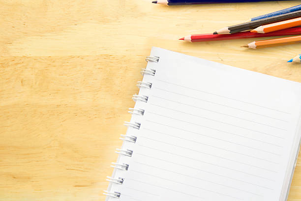 Top view notebook paper. Colorful colored Pencils on wooden table.