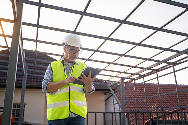 istock Senior male engineer uses tablet and blueprints to plan warehouse construction work. 2217239085