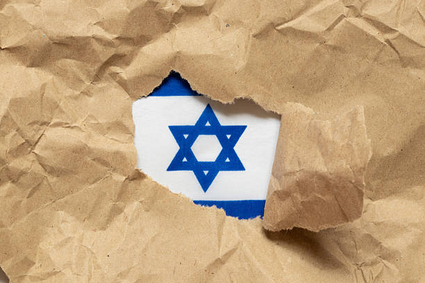 istock Flag of Israel seen through torn kraft paper as a symbol, identity 2217242555