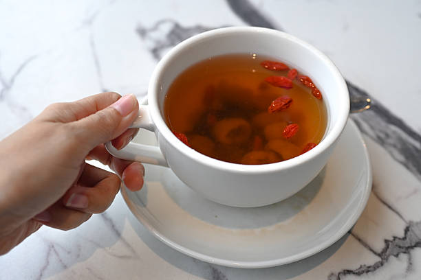 Female hands holding a white cup of tea standing on the table