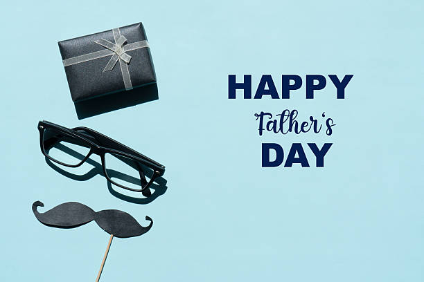 Happy Father's Day concept with gift box, eye glasses and mustache paper on blue background