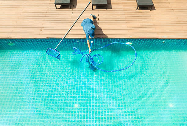 istock Pool maintenance with scoop net  and automatic robot cleaner. 2217254823