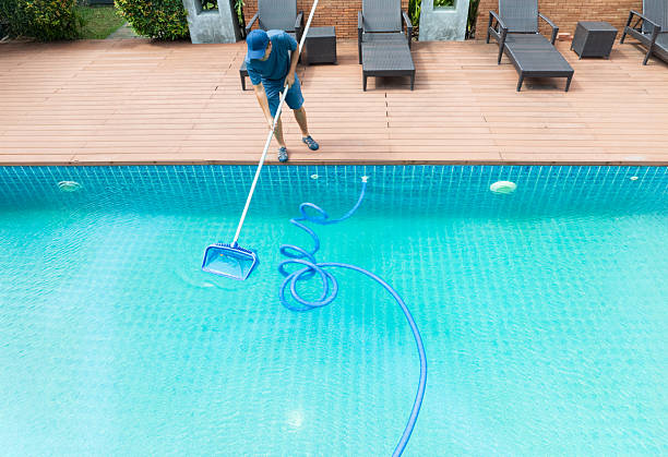 istock Pool maintenance with scoop net  and automatic robot cleaner. 2217254861