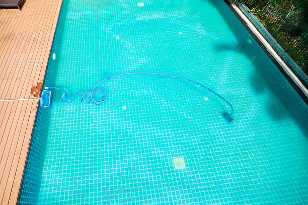 istock Pool maintenance with scoop net  and automatic robot cleaner. 2217256269