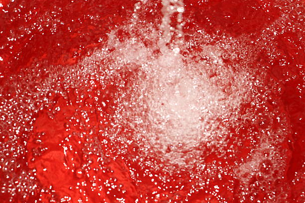 A close-up view of falling water into a red bucket. The turbulence and bubbles created by the water stream are vividly highlighted, producing a dynamic visual effect.