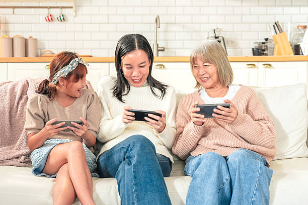 istock Asian family with smartphone game online technology Grandmother learning new technologies with granddaughters using smartphones at home Laughing intergenerational family spending leisure time 2217268604