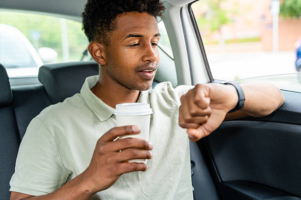 istock businessman checking time on his smartwatch while drinking coffee in a taxi 2217270114